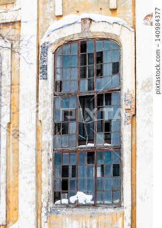 narrow window with broken glass panes in building 140984377