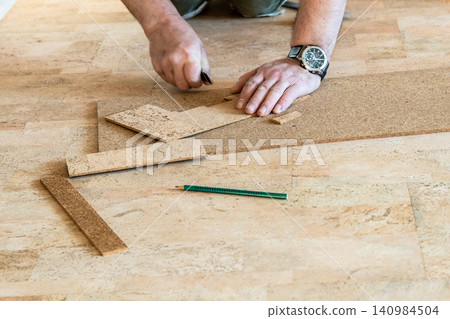 repairman cuts cork tile during flooring laying repairman cuts cork tile during flooring laying 140984504