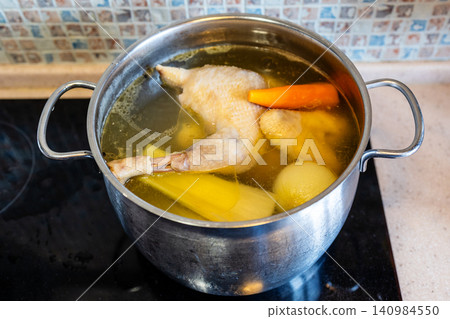 chicken broth boiling with vegetables in steel pot 140984550