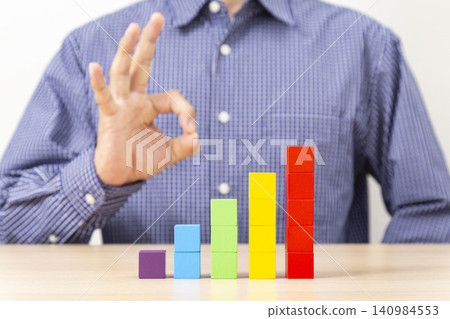 A man making an OK sign with a graph made of building blocks. A man making an OK sign with a graph made of building blocks. 140984553