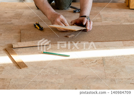 floor layer cuts cork tile during flooring laying floor layer cuts cork tile during flooring laying 140984709