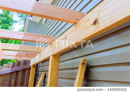 Workers are constructing wooden shed framework against house scene fresh lumber Workers are constructing wooden shed framework against house scene fresh lumber 140985082