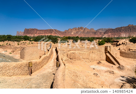Scenic view of the historical mud brick ruins of AlUla Old Town with rugged sandstone mountains in the background in Saudi Arabia. Scenic view of the historical mud brick ruins of AlUla Old Town with rugged sandstone mountains in the background in Saudi Arabia. 140985424