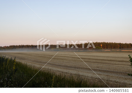 Farmland field mist and forest during sunrise Farmland field mist and forest during sunrise 140985581