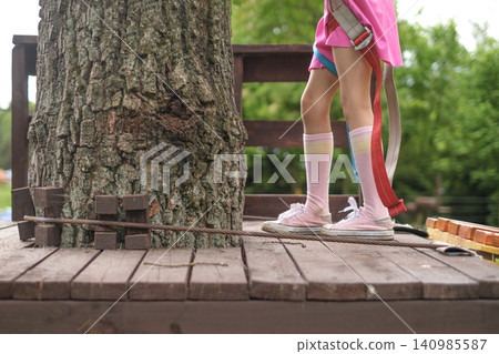A girl in sneakers on a suspension bridge in a tree, close-up A girl in sneakers on a suspension bridge in a tree, close-up 140985587
