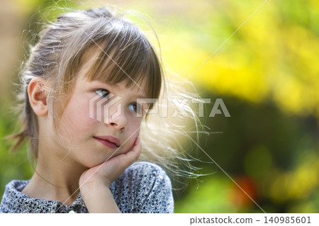 Portrait of cute pretty thoughtful child girl outdoors on blurred sunny colorful bright background. Portrait of cute pretty thoughtful child girl outdoors on blurred sunny colorful bright background. 140985601