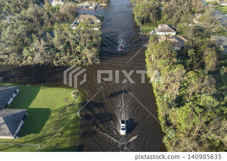 Aerial view of flooded street after hurricane rainfall with driving cars in Florida residential area. Consequences of natural disaster Aerial view of flooded street after hurricane rainfall with driving cars in Florida residential area. Consequences of natural disaster 140985635