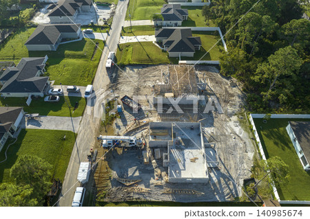 Builders working on roof construction of unfinished residential house with wooden frame structure in Florida suburban area. Housing development concept Builders working on roof construction of unfinished residential house with wooden frame structure in Florida suburban area. Housing development concept 140985674