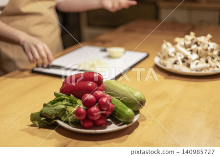 Fresh Vegetables on Plate with Person Preparing Food in Backgrou Fresh Vegetables on Plate with Person Preparing Food in Backgrou 140985727