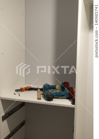 Power drills and hand tools on white shelf in workshop Power drills and hand tools on white shelf in workshop 140985741