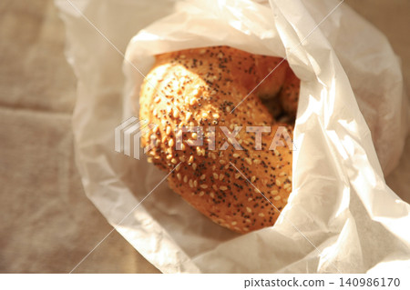 Sesame and poppy seed bagel in white paper bag Sesame and poppy seed bagel in white paper bag 140986170