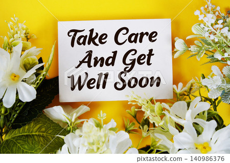 Take Care And Get Well Soon text written on paper card with flowers decoration on yellow background Take Care And Get Well Soon text written on paper card with flowers decoration on yellow background 140986376