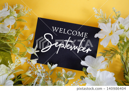 Welcome September text written on paper card with flowers decoration on yellow background Welcome September text written on paper card with flowers decoration on yellow background 140986404