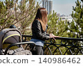 Urban park scene showing mother and child stroller overlooking city skyline 140986462
