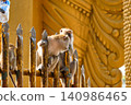 Macaques perched on vertical railings observing surroundings near temple or tourist site in Southeast Asia 140986465