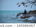 Man fishing from rocky shore at Pasir Tengkorak beach Langkawi Malaysia under clear blue sky 140986467