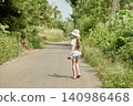 Monitor lizard running across countryside road as girl stands amazed 140986468