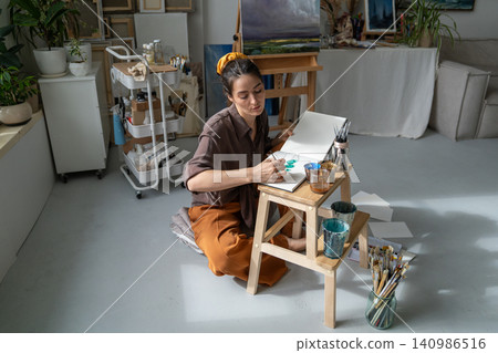 Creative working process at home gallery, thoughtful woman artist makes watercolor sketches in album Creative working process at home gallery, thoughtful woman artist makes watercolor sketches in album 140986516