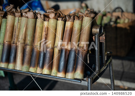 Preparation of dessert Khao Lam or Lemang, sticky rice slow-roasted inside bamboo shoots over coals Preparation of dessert Khao Lam or Lemang, sticky rice slow-roasted inside bamboo shoots over coals 140986520
