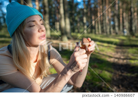 Woman hobbyist forager checking fresh Boletus edulis mushroom stem with knife for worms. Woman hobbyist forager checking fresh Boletus edulis mushroom stem with knife for worms. 140986607