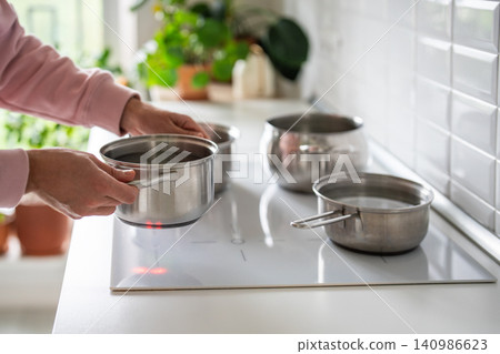 Man putting stockpot with cold water on stove to boil, scheduled hot water system outage in house. 140986623