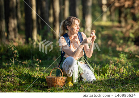 Smiling woman mushroomer forager found fresh edible boletus mushrooms in autumn pine forest. Smiling woman mushroomer forager found fresh edible boletus mushrooms in autumn pine forest. 140986624