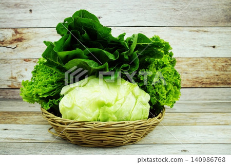 Fresh raw Iceberg, Romaine and Green Cos lettuces in bamboo basket on wooden background Fresh raw Iceberg, Romaine and Green Cos lettuces in bamboo basket on wooden background 140986768