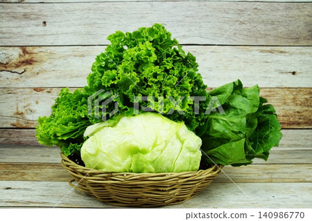 Fresh raw Iceberg, Romaine and Green Cos lettuces in bamboo basket on wooden background Fresh raw Iceberg, Romaine and Green Cos lettuces in bamboo basket on wooden background 140986770