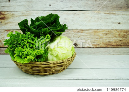 Fresh raw Iceberg, Romaine and Green Cos lettuces in bamboo basket on wooden background Fresh raw Iceberg, Romaine and Green Cos lettuces in bamboo basket on wooden background 140986774