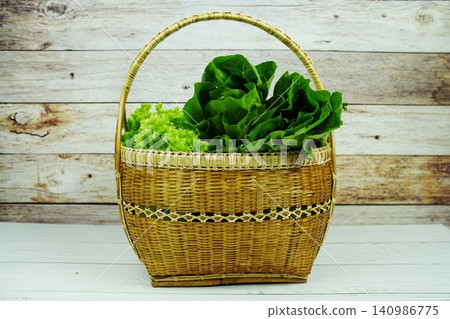 Fresh raw Iceberg, Romaine and Green Cos lettuces in bamboo basket on wooden background Fresh raw Iceberg, Romaine and Green Cos lettuces in bamboo basket on wooden background 140986775