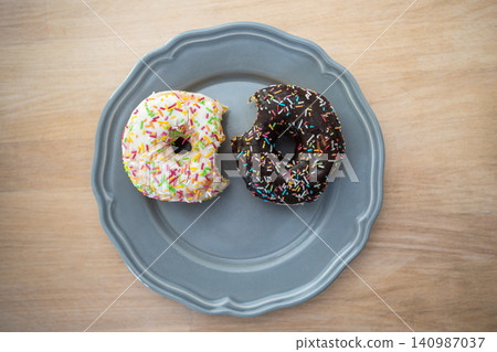 Junk food, unhealthy eating and sugar addiction, plate with two bitten chocolate glazed doughnuts. Junk food, unhealthy eating and sugar addiction, plate with two bitten chocolate glazed doughnuts. 140987037
