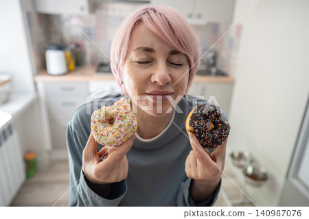 Smiling pleased mature woman sweet tooth tasting chocolate glazed doughnuts with pure satisfaction. Smiling pleased mature woman sweet tooth tasting chocolate glazed doughnuts with pure satisfaction. 140987076