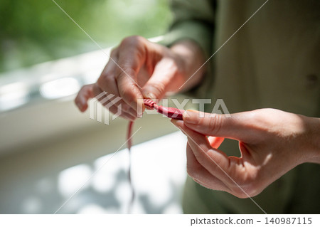Woman hands holding showing smartphone charging cable with damaged winding near plug connection Woman hands holding showing smartphone charging cable with damaged winding near plug connection 140987115