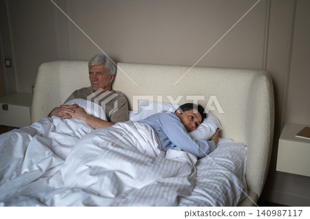 Exhausted elderly married lying in bed with frustration and disappointment after arguing. 140987117