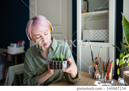 Relaxed mature woman plant lover enjoying indoor garden hobby, holding box with growing seedlings Relaxed mature woman plant lover enjoying indoor garden hobby, holding box with growing seedlings 140987134