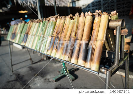 Cooking of exotic Asian dish Khao Lam, bamboo tubes filled with sticky rice roasting on hot coals Cooking of exotic Asian dish Khao Lam, bamboo tubes filled with sticky rice roasting on hot coals 140987141