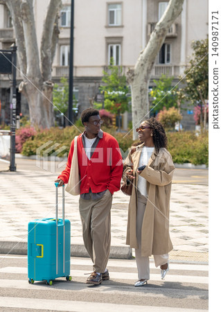 Happy married african american man and woman smiling and talking while walking through street Happy married african american man and woman smiling and talking while walking through street 140987171