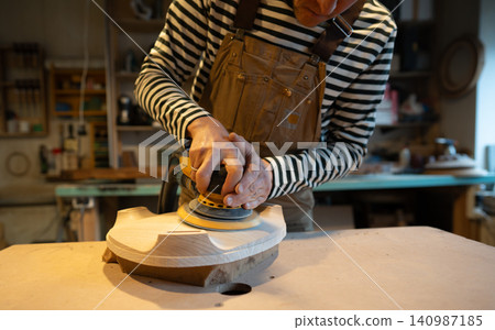 Sanding wood with orbital sander at workshop. Carpentry workshop. Furniture production Sanding wood with orbital sander at workshop. Carpentry workshop. Furniture production 140987185