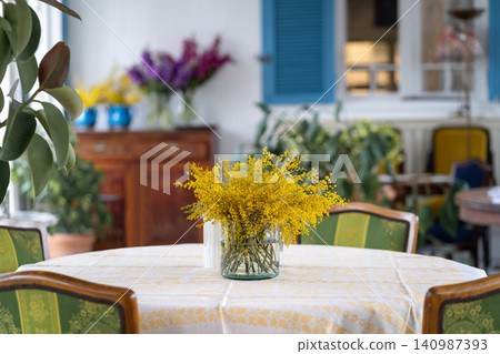 Bouquet of Mimosa flower in glass vase on table in cafe or restaurant. Spring, 8 March, Easter. Bouquet of Mimosa flower in glass vase on table in cafe or restaurant. Spring, 8 March, Easter. 140987393