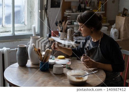 Craftswoman takes paintbrush to make interesting pattern on dish created for kitchen furniture Craftswoman takes paintbrush to make interesting pattern on dish created for kitchen furniture 140987412