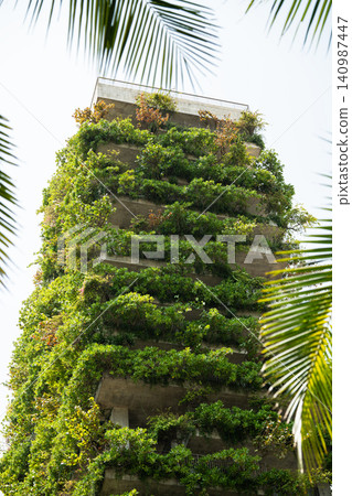 Building with vertical garden, balconies filled with greenery cascading from apartment terraces. Building with vertical garden, balconies filled with greenery cascading from apartment terraces. 140987447