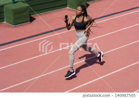 African woman athlete running on racetrack. Sportive black female training jog on stadium sprinting African woman athlete running on racetrack. Sportive black female training jog on stadium sprinting 140987505