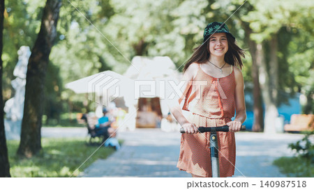 Happy teenager riding an electric scooter in a park during summer, enjoying sustainable transportation and outdoor leisure activity Happy teenager riding an electric scooter in a park during summer, enjoying sustainable transportation and outdoor leisure activity 140987518