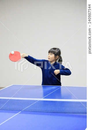 A female elementary school student (7 years old) playing table tennis. A female elementary school student (7 years old) playing table tennis. 140987544