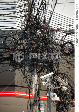 Messy tangled electricity wires and data cables on pole, asian urban landmark at street in city. Messy tangled electricity wires and data cables on pole, asian urban landmark at street in city. 140987634