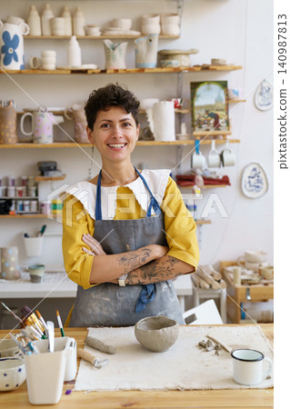 Young girl ceramics and pottery studio owner in workshop. Female craft crockery master at workplace Young girl ceramics and pottery studio owner in workshop. Female craft crockery master at workplace 140987813