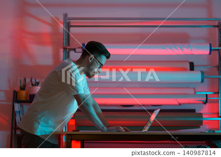 Young fashion designer tailor use laptop to order fabrics for clothes collection online in studio Young fashion designer tailor use laptop to order fabrics for clothes collection online in studio 140987814