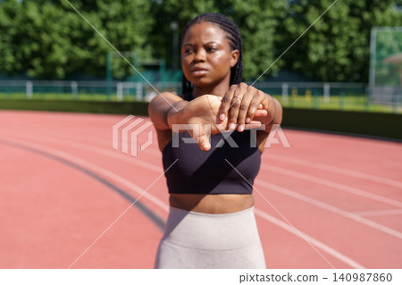 African American female stretches hands warming up before intensive workout on sunny summer day African American female stretches hands warming up before intensive workout on sunny summer day 140987860