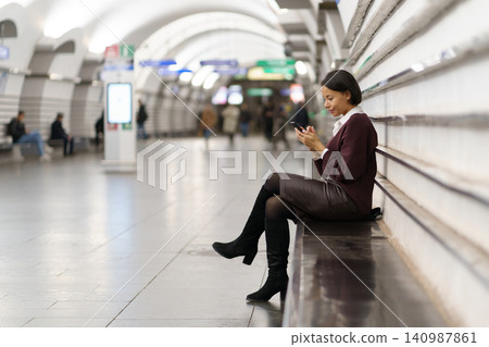 Smiling american woman using smartphone at subway station, afro female with cellphone in underground Smiling american woman using smartphone at subway station, afro female with cellphone in underground 140987861