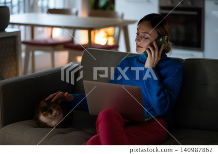 Young businesswoman stroking cat head on sofa talks with colleague discussing business project Young businesswoman stroking cat head on sofa talks with colleague discussing business project 140987862